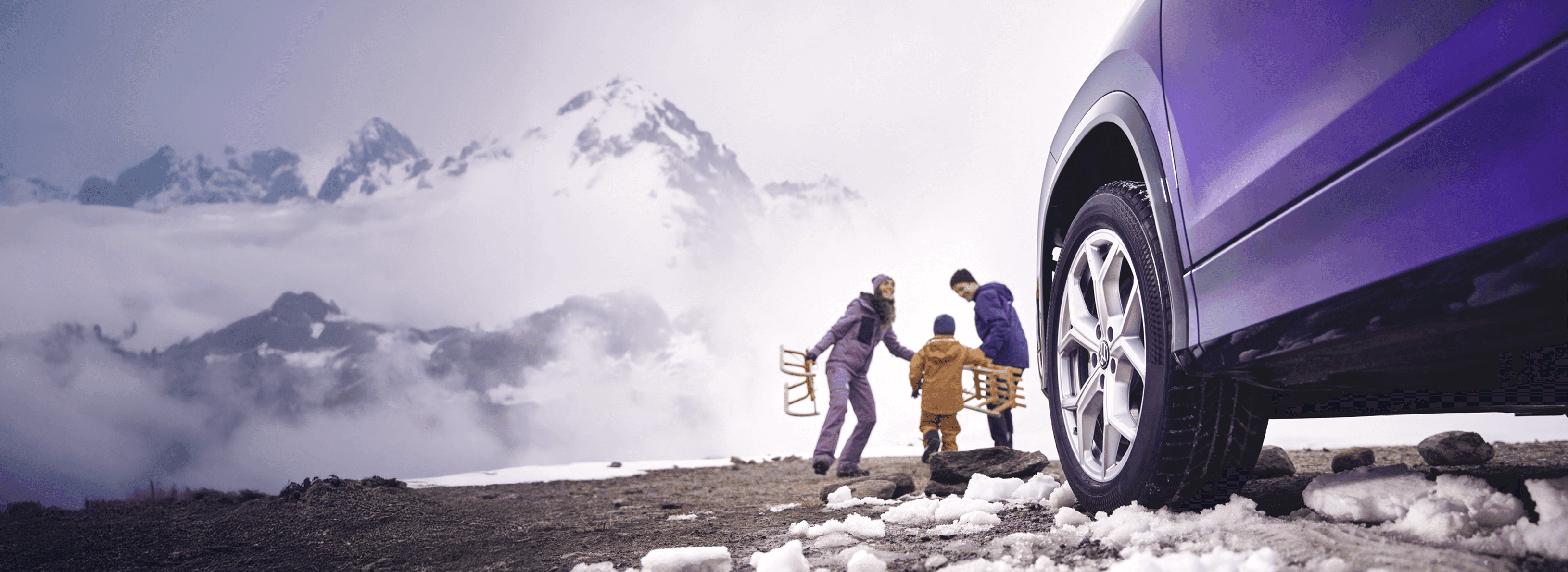 Dwa samochody w górach, w tle ośnieżone szczyty.